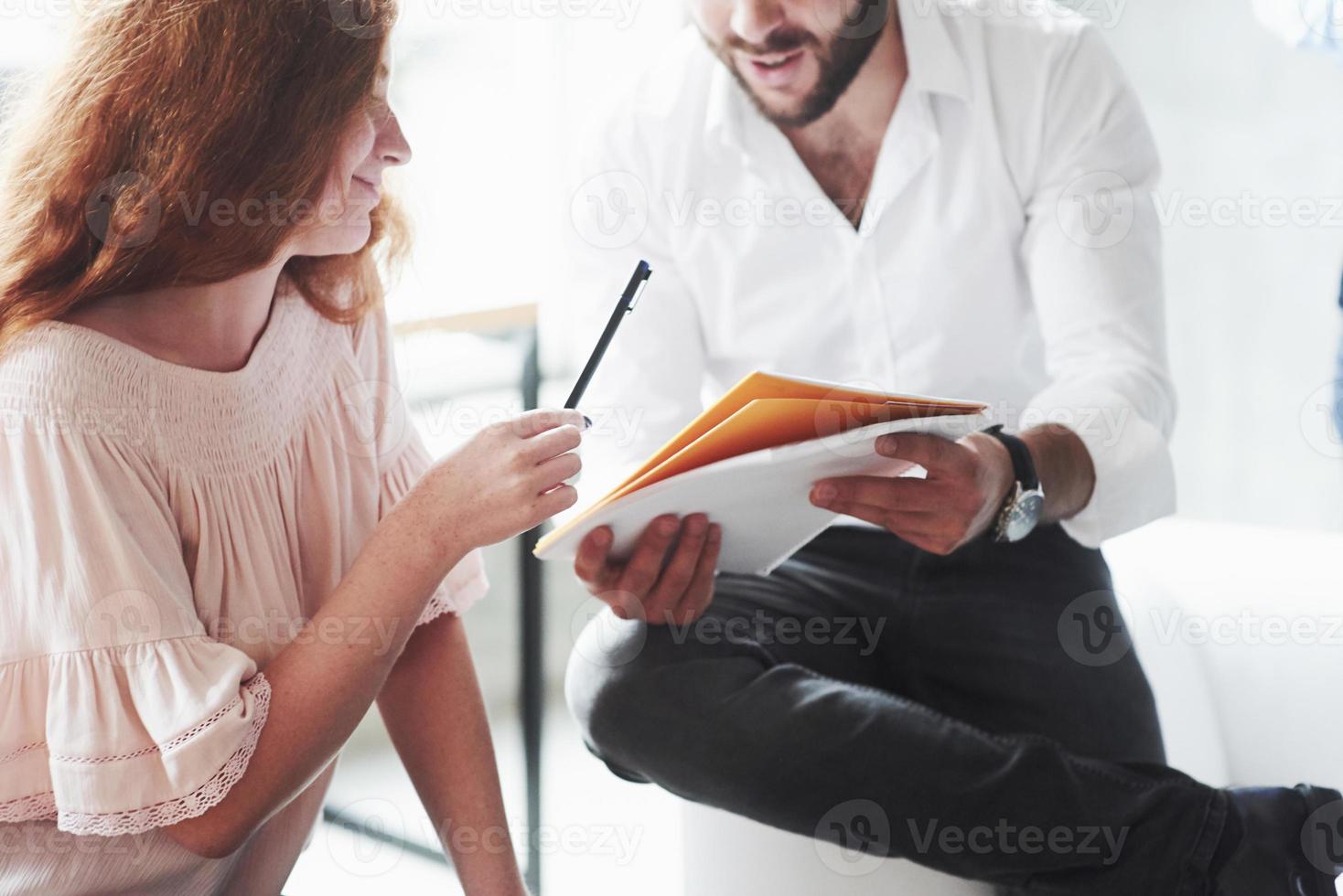 aquí hay lápiz para las correcciones. pelirroja y barbudo sentado en el sofá y conversando sobre su proyecto foto