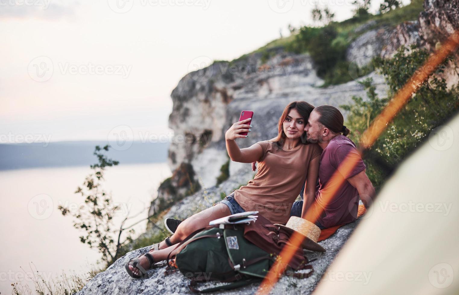 Let's take selfie. Two person sitting on the rock and watching gorgeous nature photo