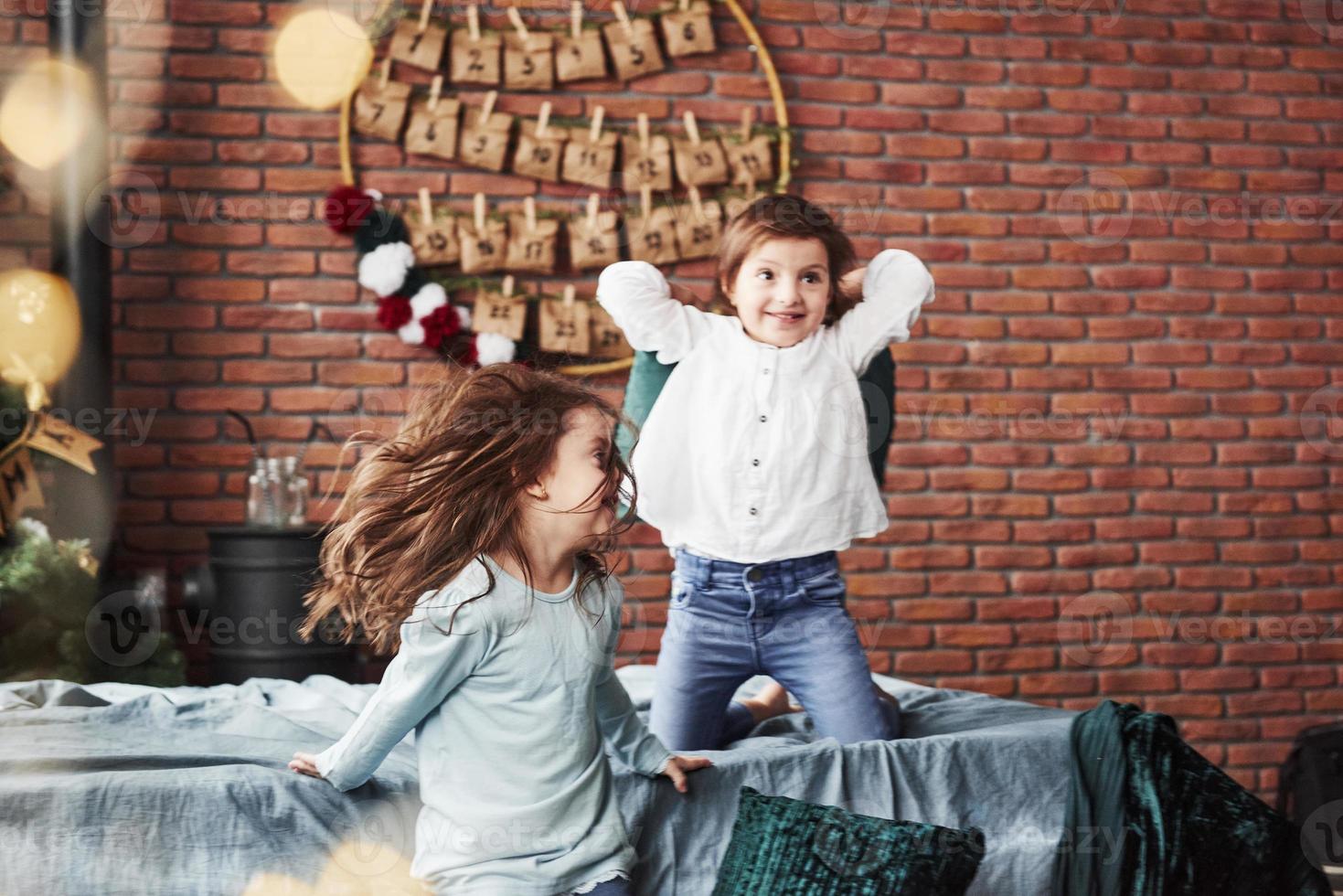 Kid jumping off the sofa. Little girls having fun on the bed with holiday interior at the background photo