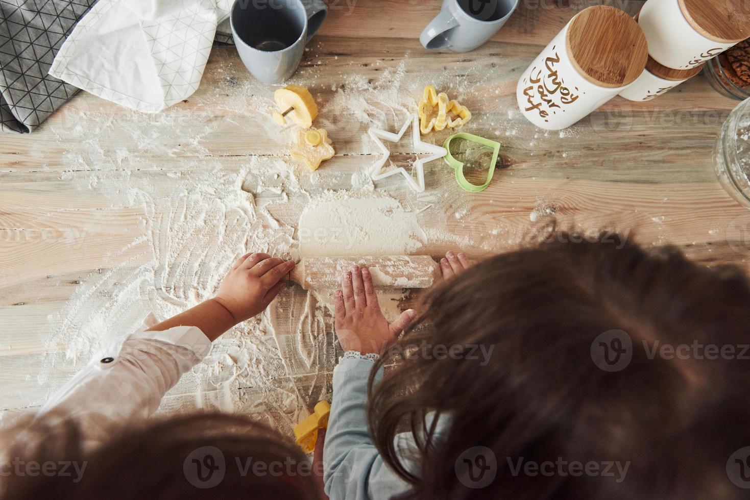 concepción de la cocina. Vista superior de los niños que aprenden a preparar alimentos a partir de la harina con instrumentos especiales. foto