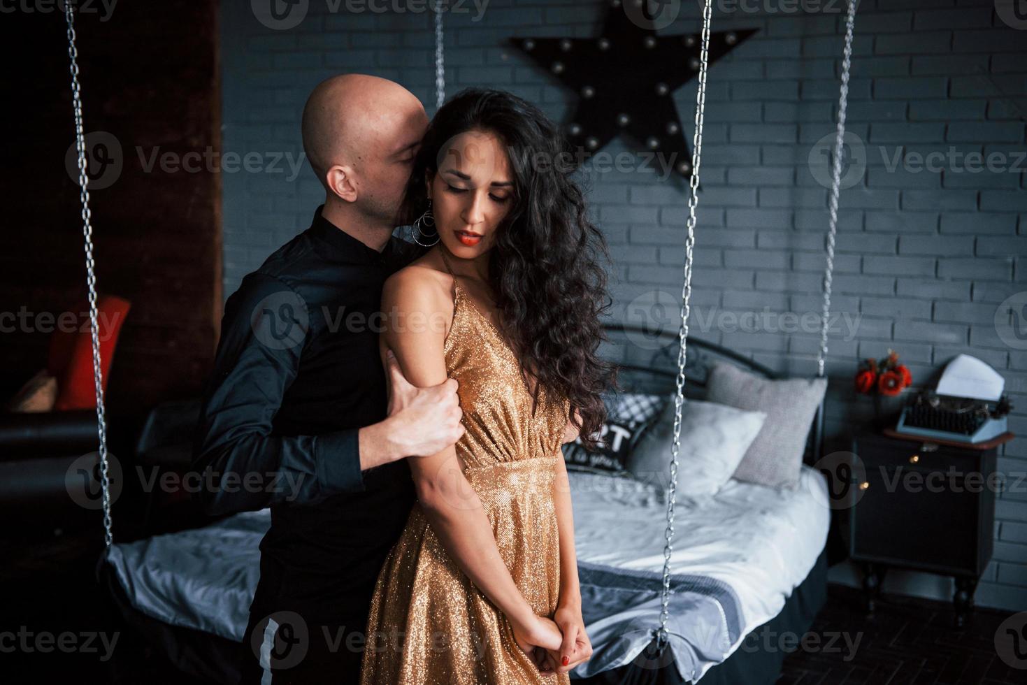 True meaning of passion. Couple in classic wear stands in front of the beautiful luxury decorated bed photo