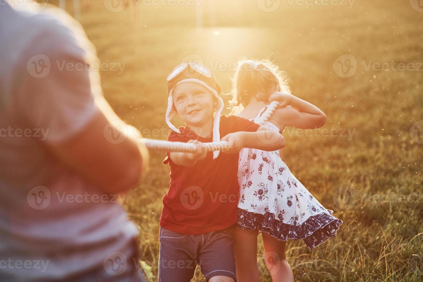 Muy divertido. esto es tira y afloja con papá en la hermosa hierba de un día cálido y soleado. foto