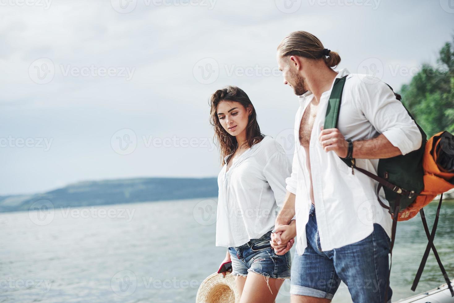 Alegre paseo de la encantadora pareja en el exterior en el fondo del lago foto