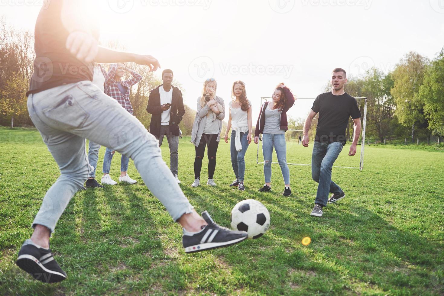 A group of friends in casual outfit play soccer in the open air. People have fun and have fun. Active rest and scenic sunset photo