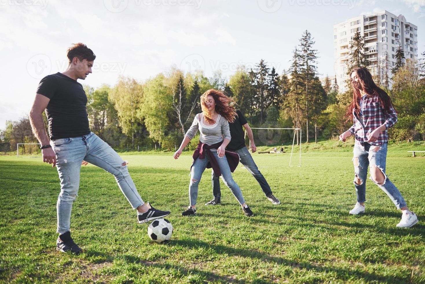 un grupo de amigos en ropa casual juega al fútbol al aire libre. la gente se divierte y se divierte. descanso activo y puesta de sol escénica foto