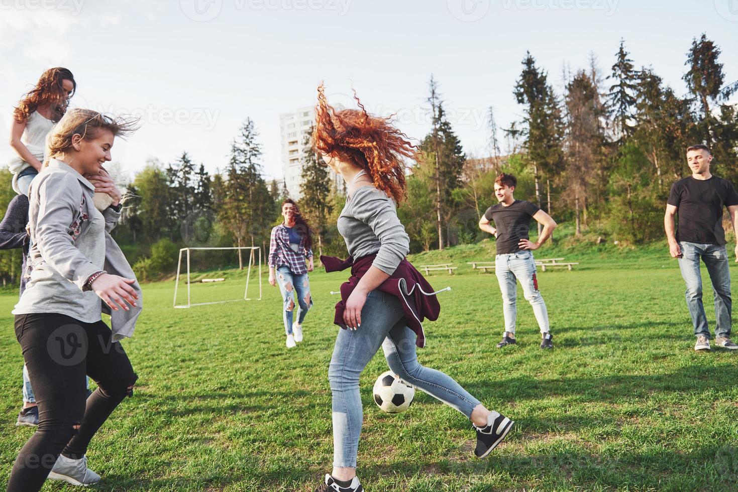 un grupo de amigos en ropa casual juega al fútbol al aire libre. la gente se divierte y se divierte. descanso activo y puesta de sol escénica foto