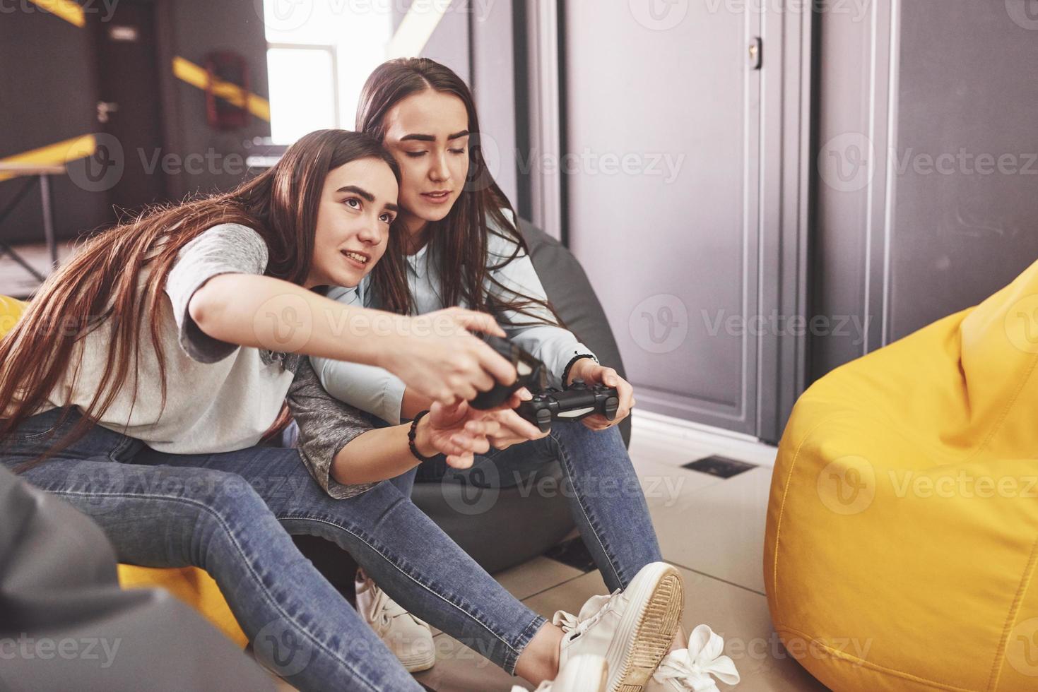 hermanas gemelas juegan en la consola. las niñas sostienen joysticks en sus manos y se divierten foto