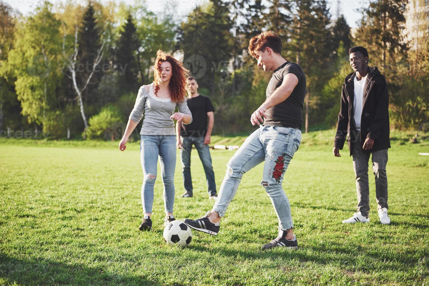 un grupo de amigos en ropa casual juega al fútbol al aire libre. la gente se divierte y se divierte. descanso activo y puesta de sol escénica foto