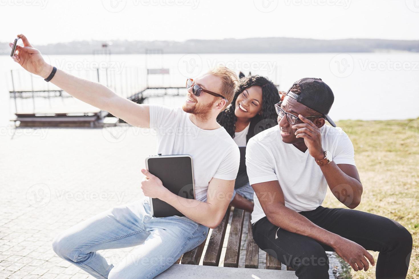 Beautiful multi ethnic friends using a laptop in the Street and make selphie. Youth lifestyle concept photo