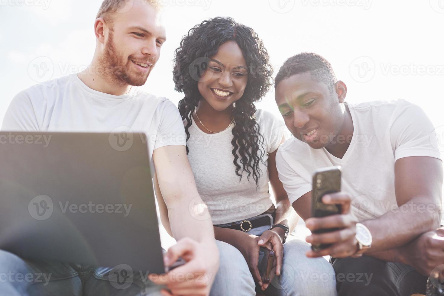 Beautiful multi ethnic friends using a laptop in the Street. Youth lifestyle concept photo