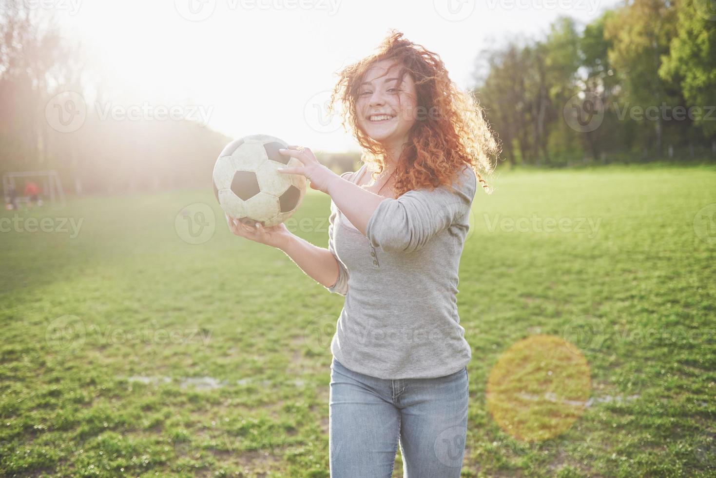 Chica sexy pelirroja joven en jugador casual en el estadio de fútbol al atardecer foto