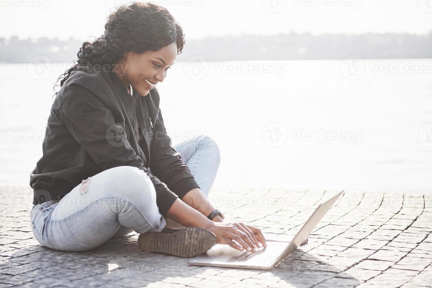 Young woman on the street working on laptop photo