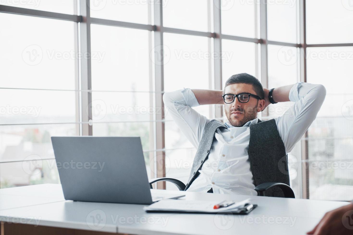 Worker is a young man with a laptop in the office photo