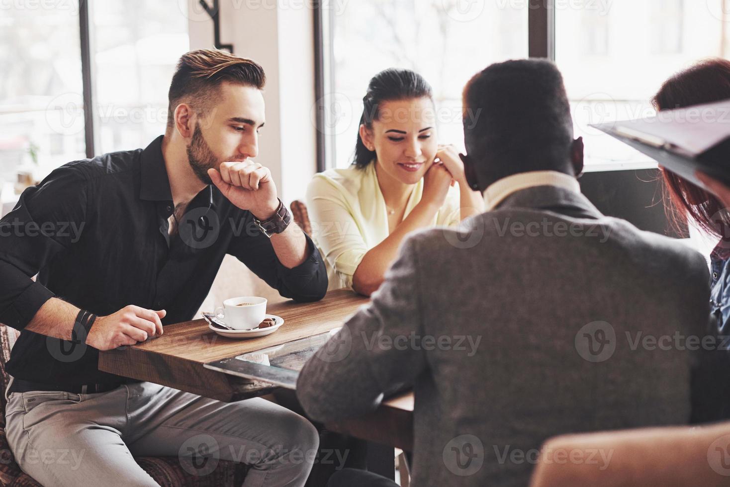 Multi ethnic people entrepreneur, small business concept. Woman showing coworkers something on laptop computer as they gather around a conference table photo