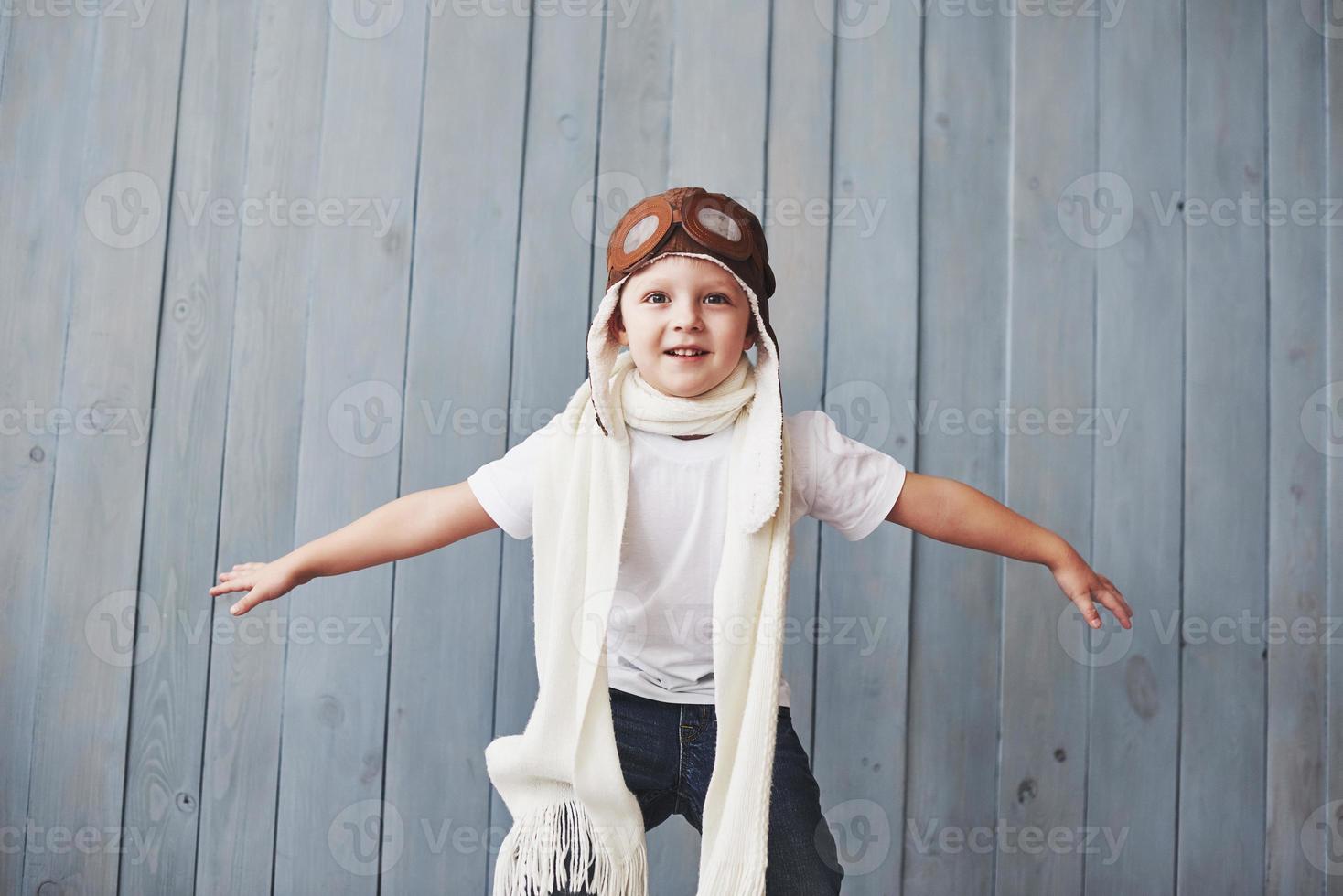 hermoso niño sonriente en casco sobre un fondo azul jugando con un avión. concepto piloto vintage foto