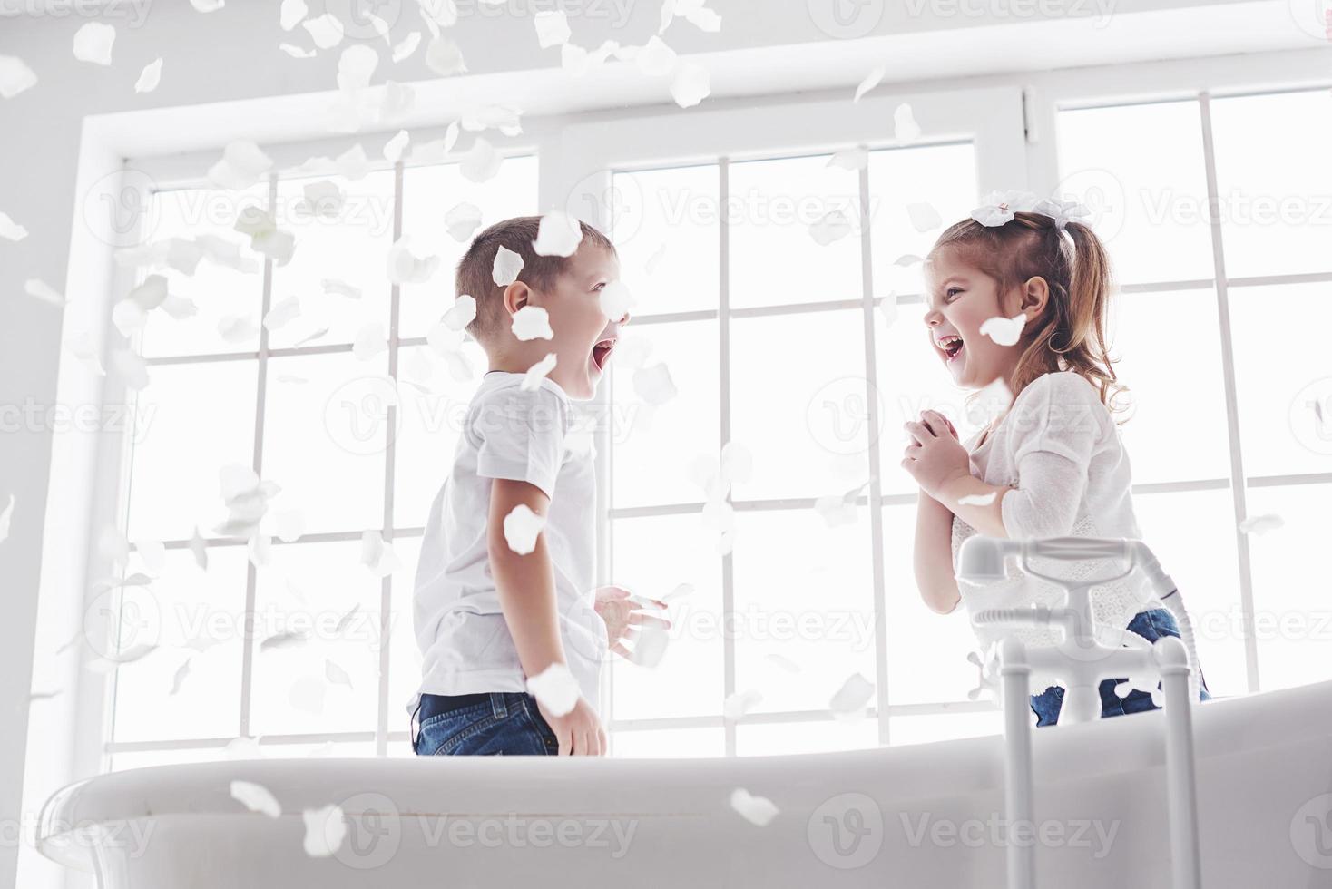 Child playing with rose petals in home bathroom. Little girl and boy fawing fun and joy together. The concept of childhood and the realization of dreams, fantasy, imagination photo