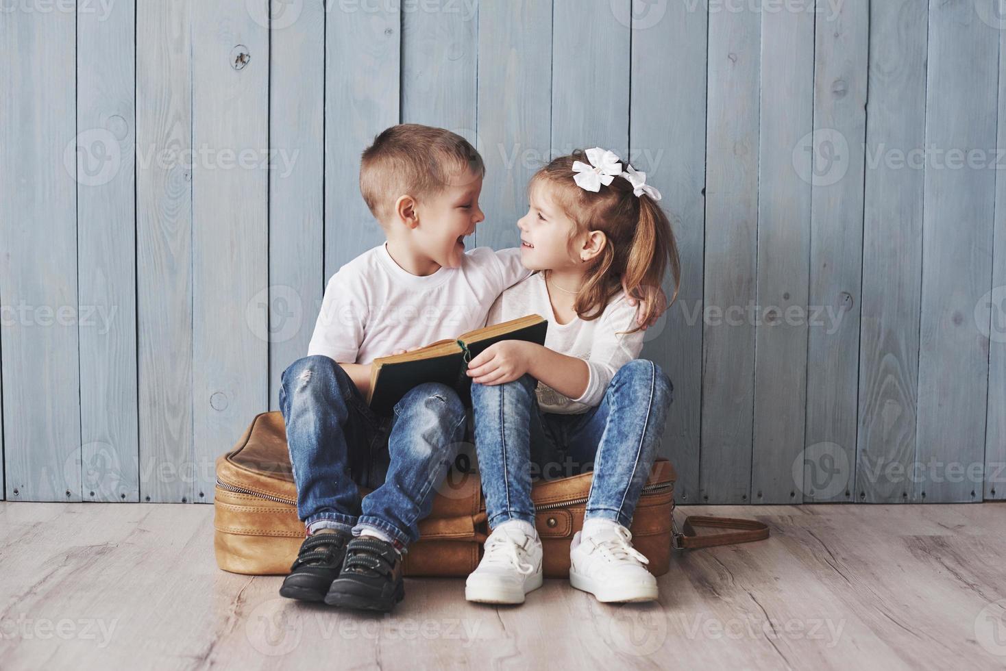 Ready to big travel. Happy little girl and boy reading interesting book carrying a big briefcase. Freedom and imagination concept photo