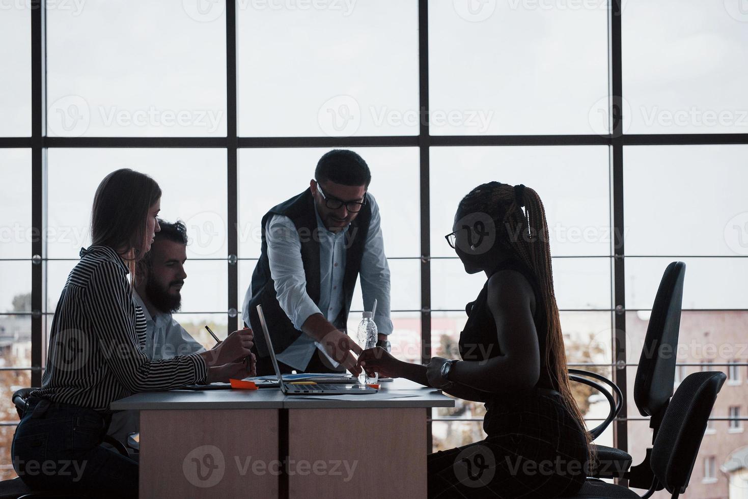 jóvenes empleados sentados en la oficina en la mesa y usando una computadora portátil, un concepto de reunión de intercambio de ideas de trabajo en equipo. foto