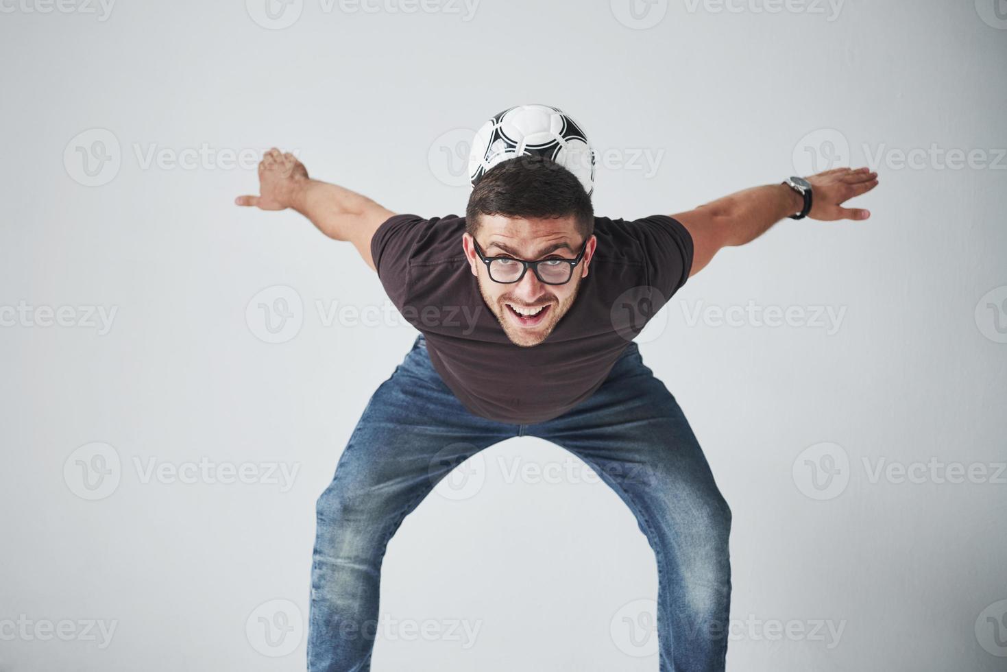 Aficionado al fútbol emocionado con un balón de fútbol aislado sobre fondo blanco. salta es feliz y realiza varios trucos de animar a su equipo favorito foto