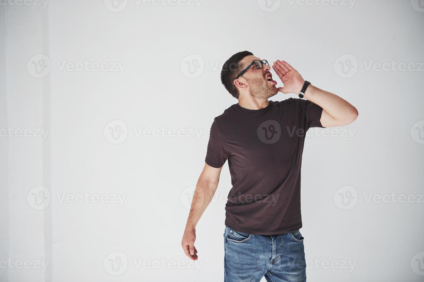 Emotional man in casual clothes loudly screams as if someone is calling. His feelings are overwhelming photo
