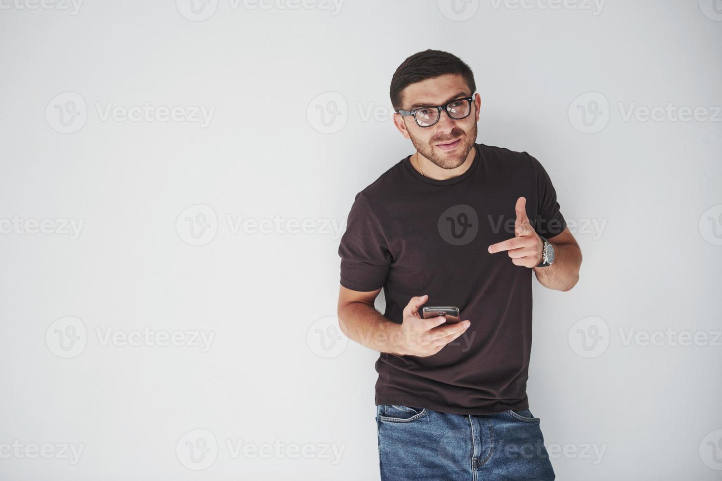 Feliz joven casual vestido con teléfono inteligente sobre fondo blanco. foto