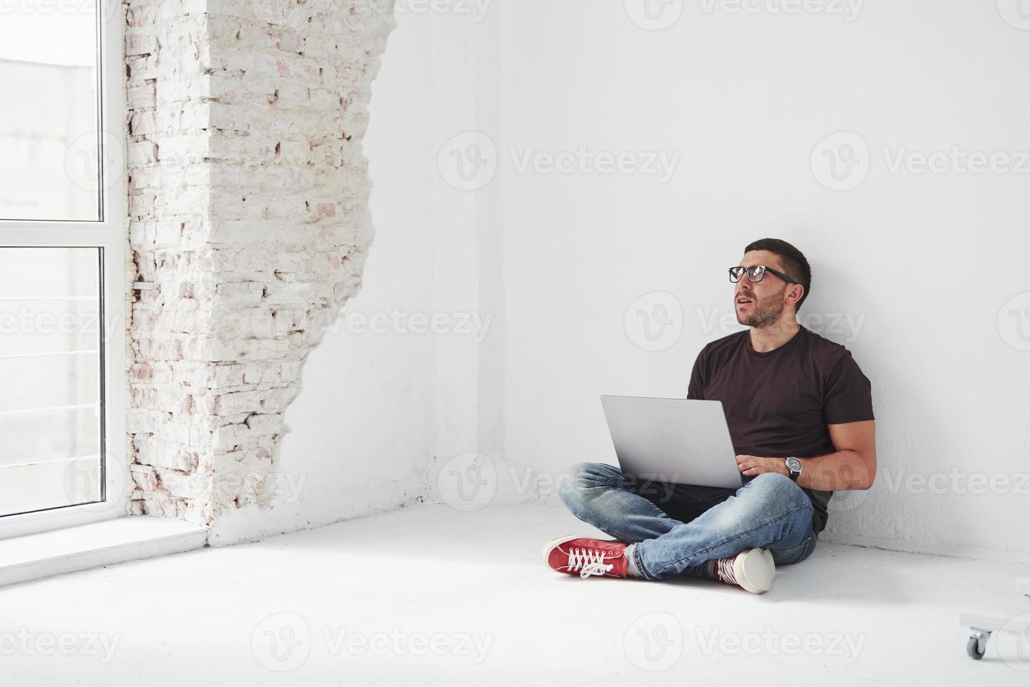 Handsome young man with laptop and check his timetable on white background photo