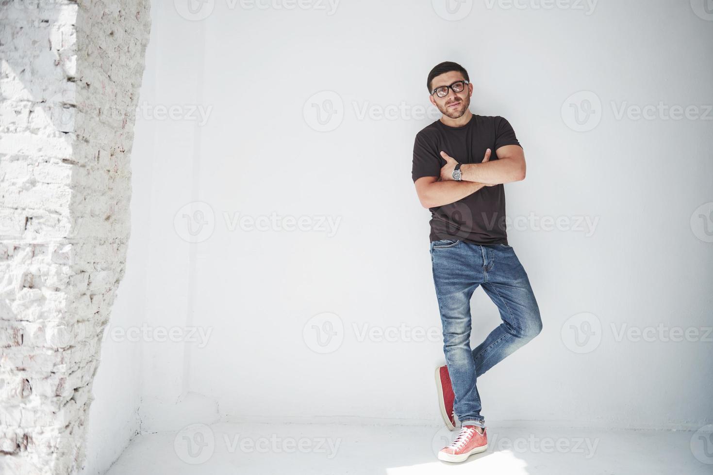 Chico joven inconformista con gafas riendo felizmente aislado sobre fondo blanco. foto