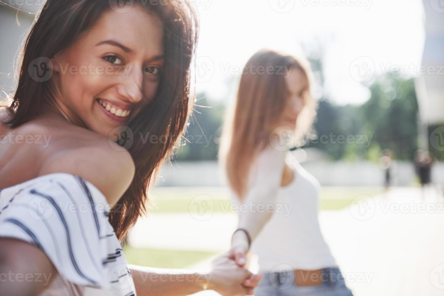 una vista cercana a dos hermosas chicas se dan la mano y pasean por las calles. tal vez tengan un amor lésbico o solo sean amigas foto