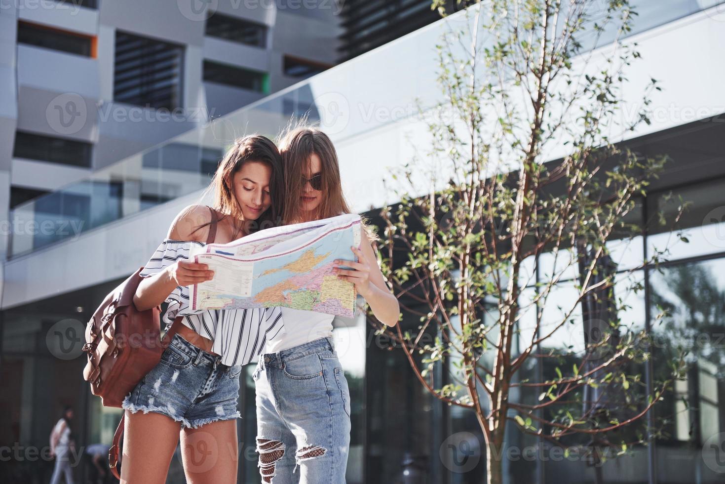 Two female tourist with map visiting a new city and is looking for a way to the hotel photo