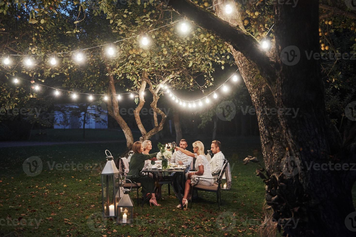 Luxury dinner. Evening time. Friends have a dinner in the gorgeous outdoor place photo