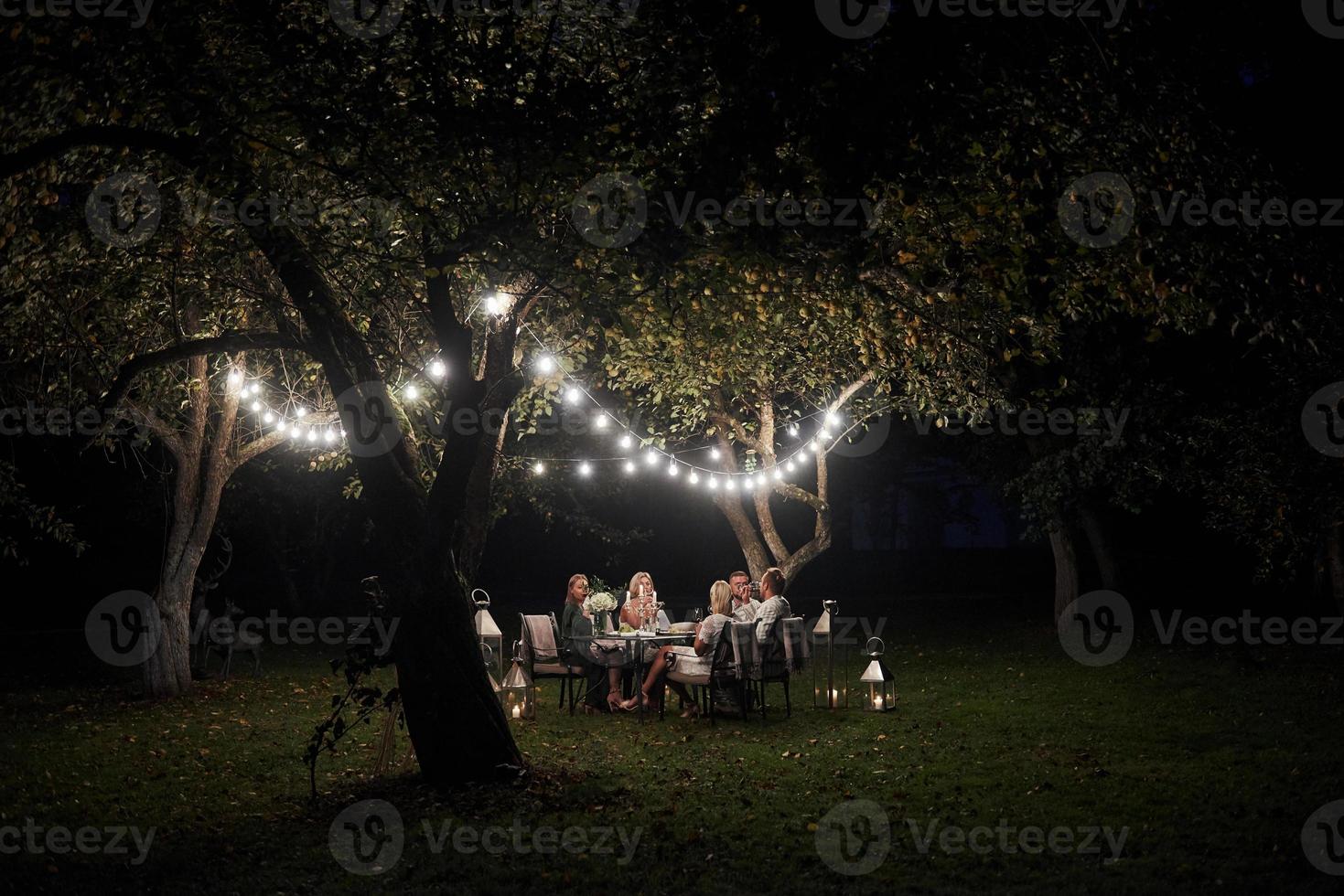 A secluded spot. Evening time. Friends have a dinner in the gorgeous outdoor place photo