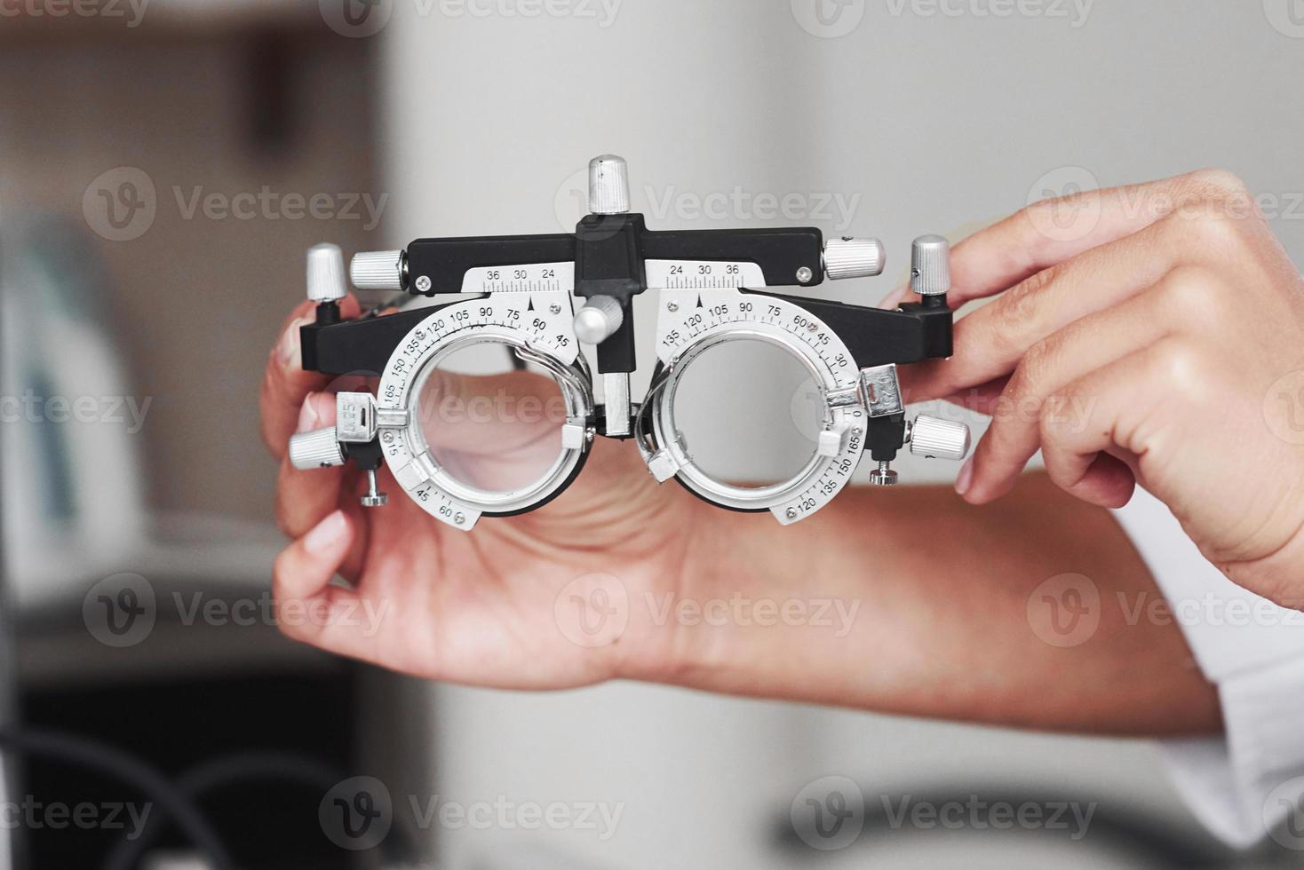 Focused photo. Female hands holding the optical device for eye testing photo