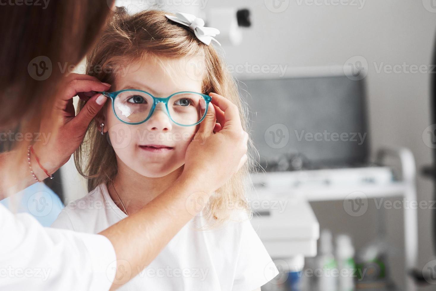 Nuevo estilo. doctor dando al niño anteojos nuevos para su visión foto