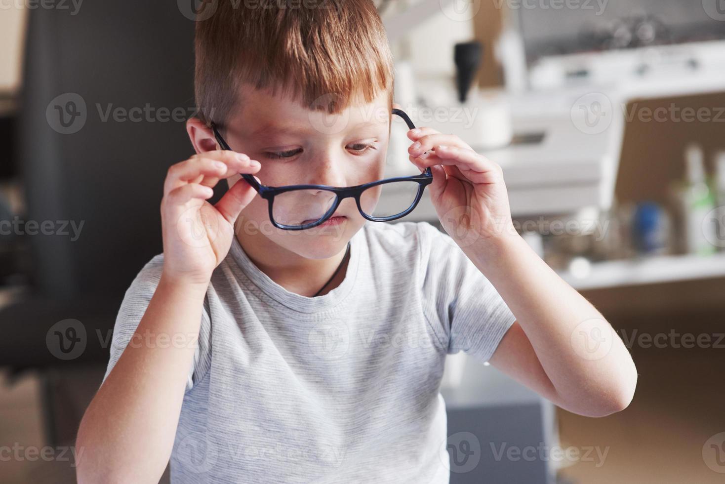 niño probándose sus nuevas gafas en el gabinete del médico foto