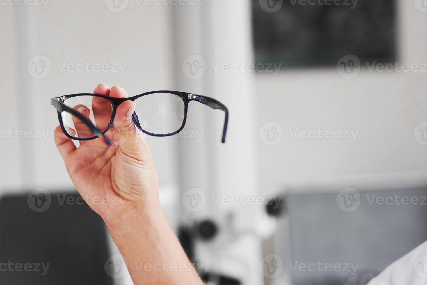 Focused photo. Woman hand holds the blue eyeglasses in the doctor cabinet photo