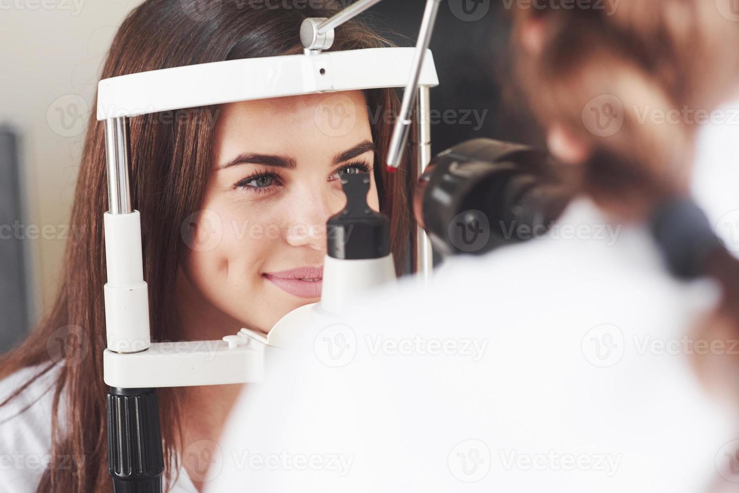 no te muevas. Optometrista comprobando la visión de la joven y bella mujer foto