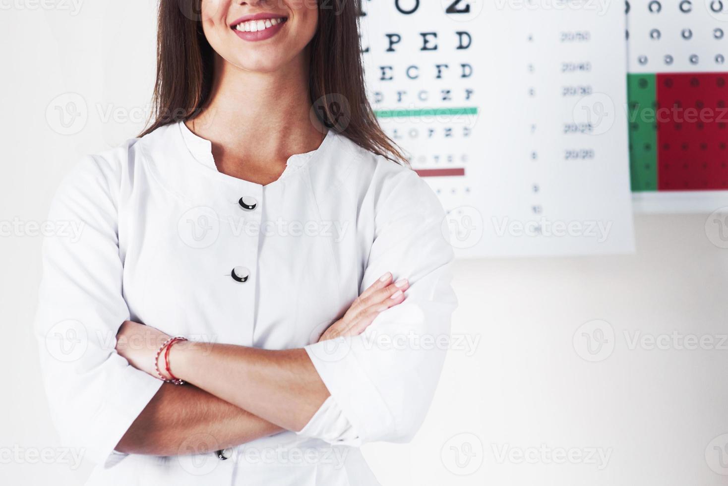 Cropped photo of gorgeous female ophthalmologist standing in the background of board with letters