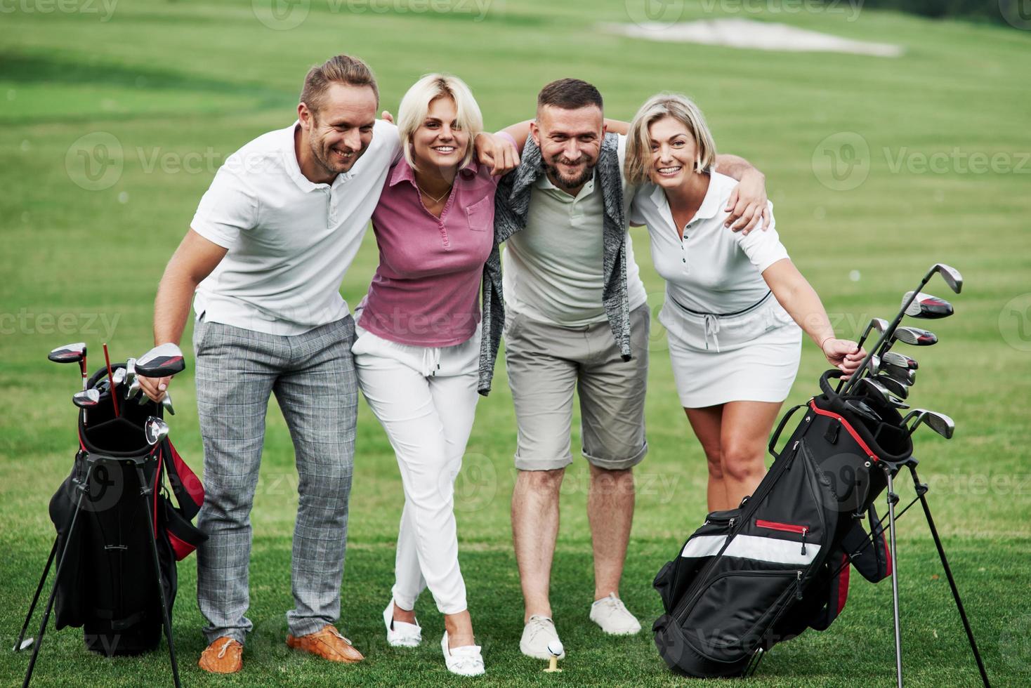 Foto de amigos abrazándose y sonriendo con equipo de golf después del juego