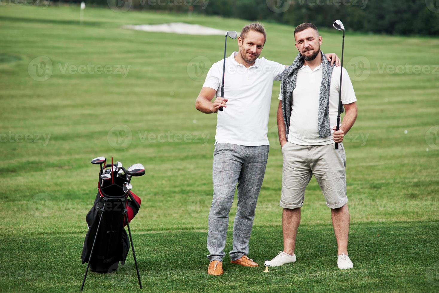 Frinendship between two golfers standing on beautiful green lawn photo