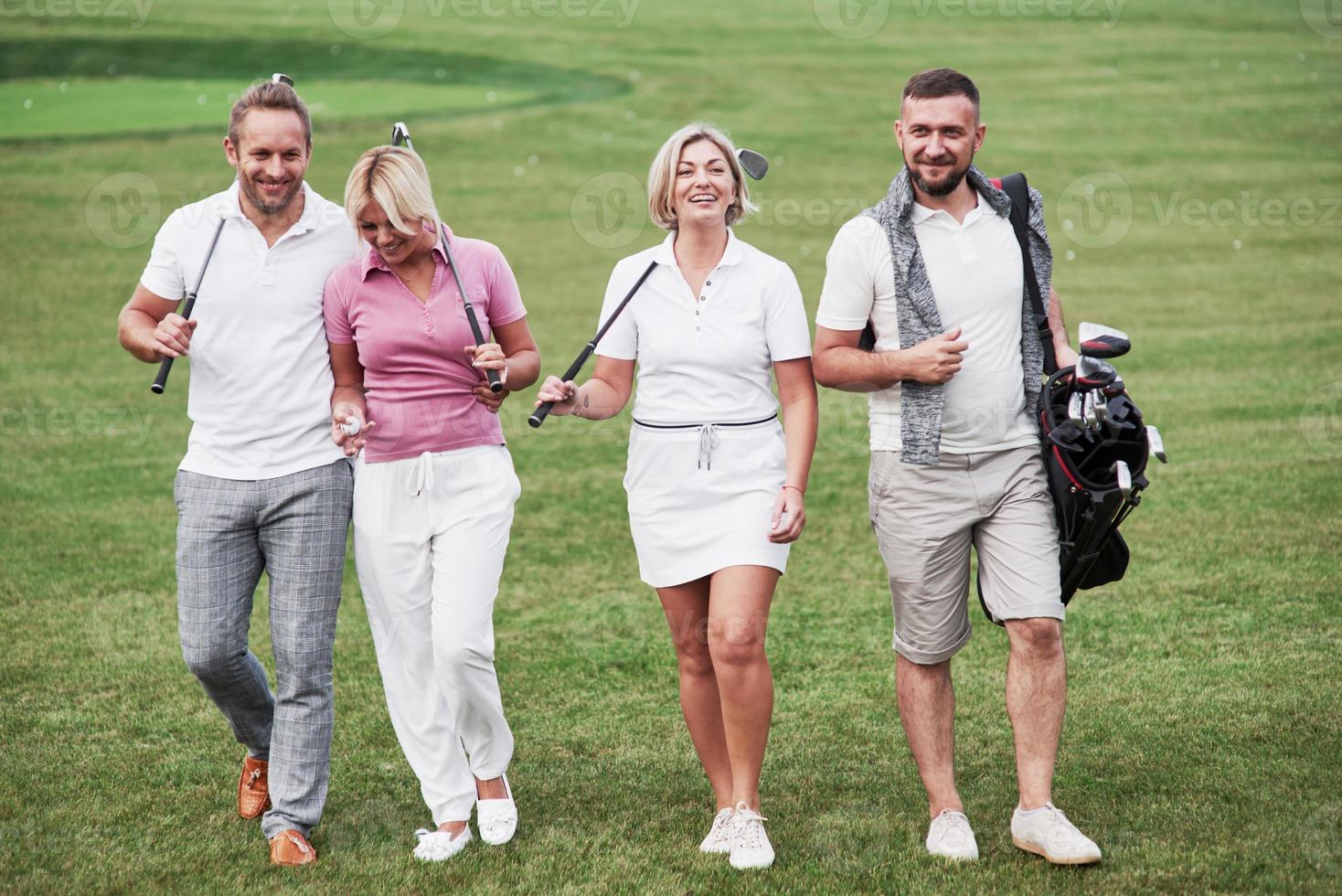 amigos alegres pasar tiempo en el campo de golf con palos y buen humor foto