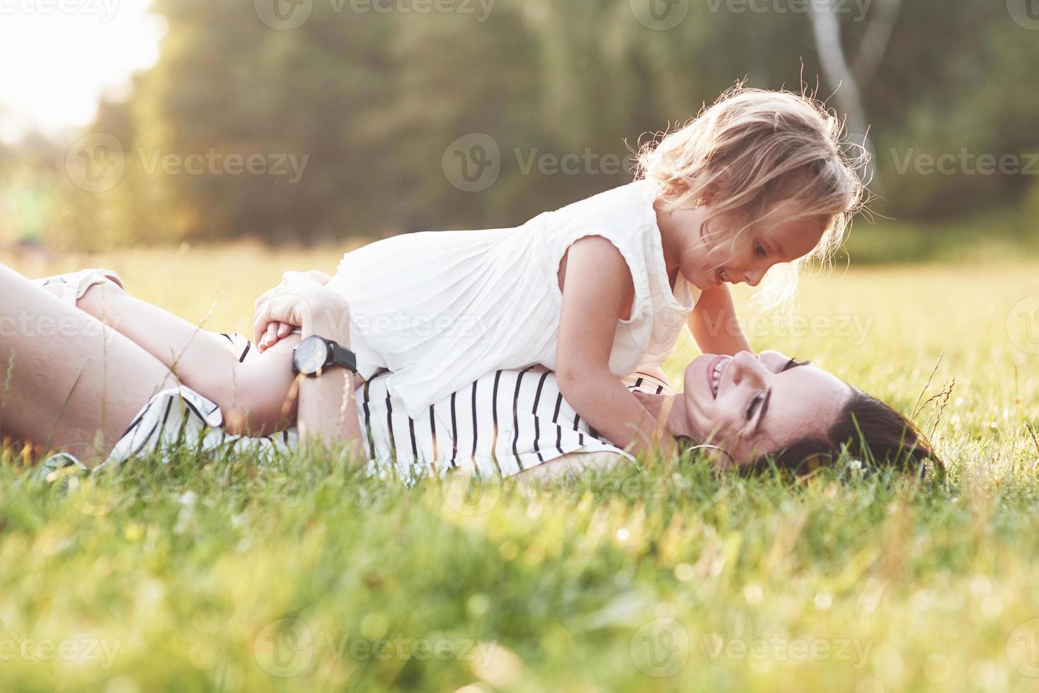 Acuéstese en la hierba. Precioso retrato de niña y su hija se abrazan afuera foto