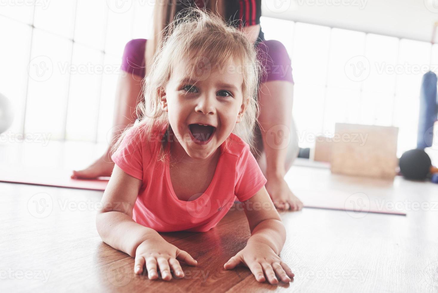 Linda niña feliz mirando directamente a la cámara y sonriendo con mamá sentada detrás foto