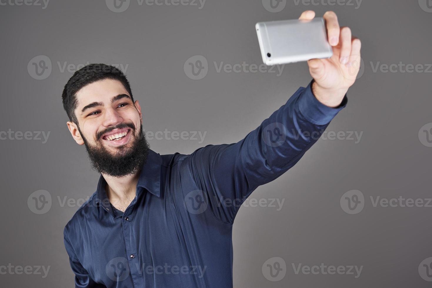 Happy smiling handsome bearded young man making selfie photo