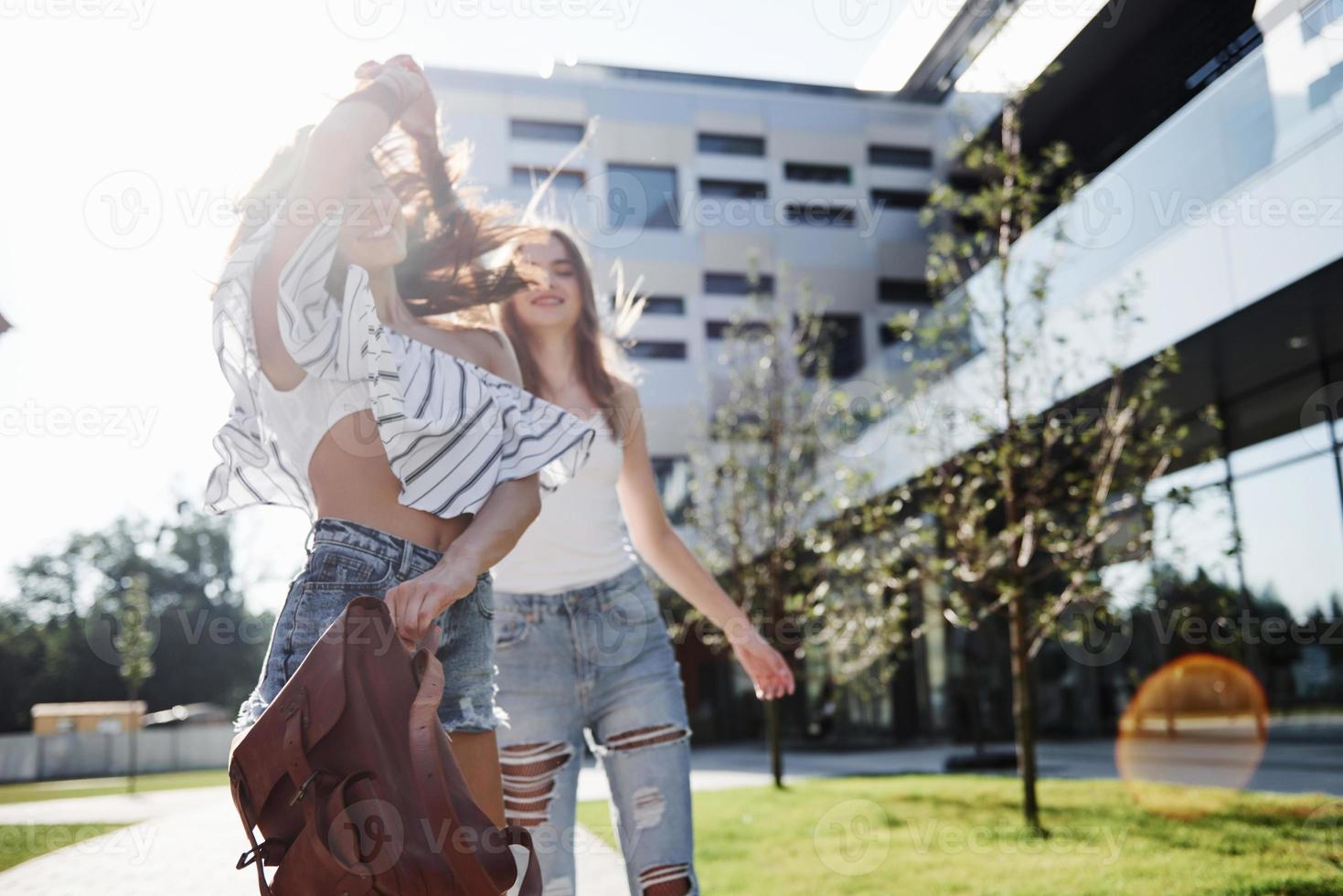 dos hermosas chicas con mochilas caminan juntas en la ciudad. amigos muy lindos comparten secretos foto