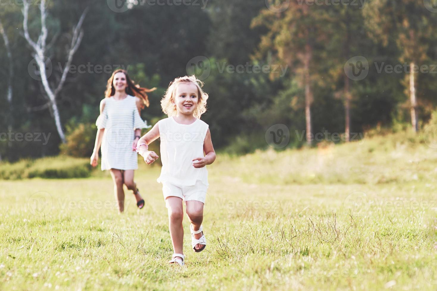 Mamá y niña tienen caminar afuera en el campo y el bosque en el fondo foto