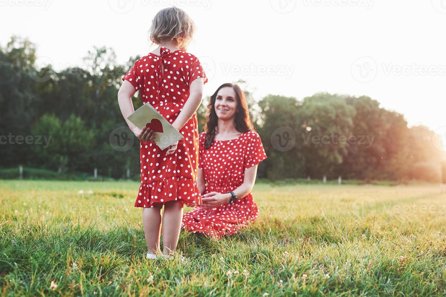 It's mine. Girl hides the book with red heart on the back from the smiling sitting mother photo