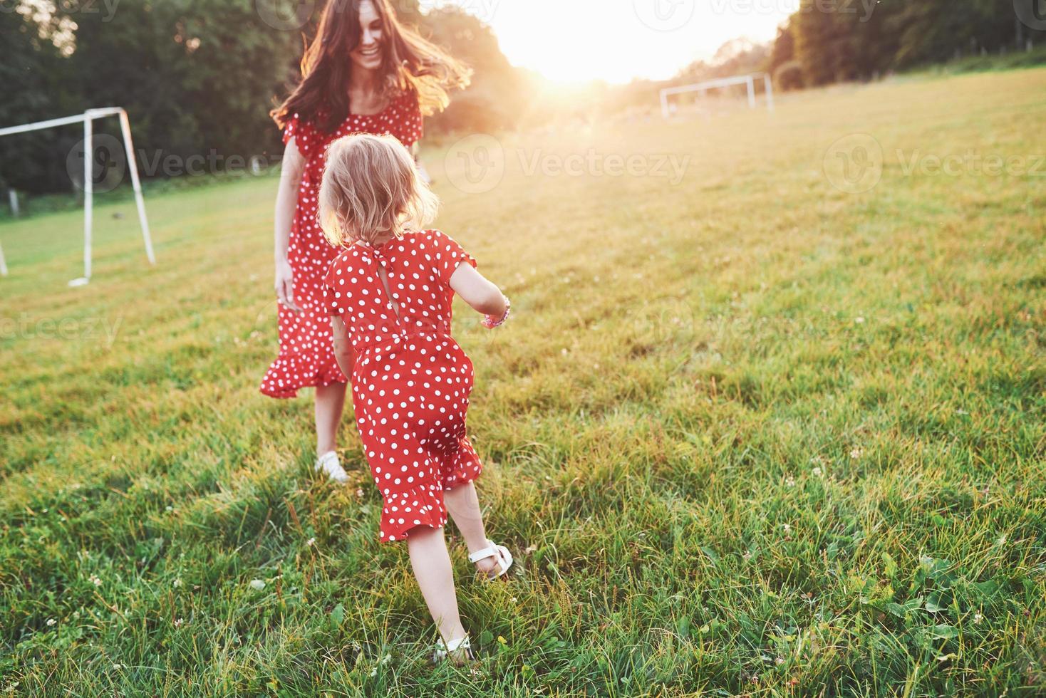 correr y divertirse. joven madre con su hija pasando tiempo afuera en un lugar tan hermoso foto