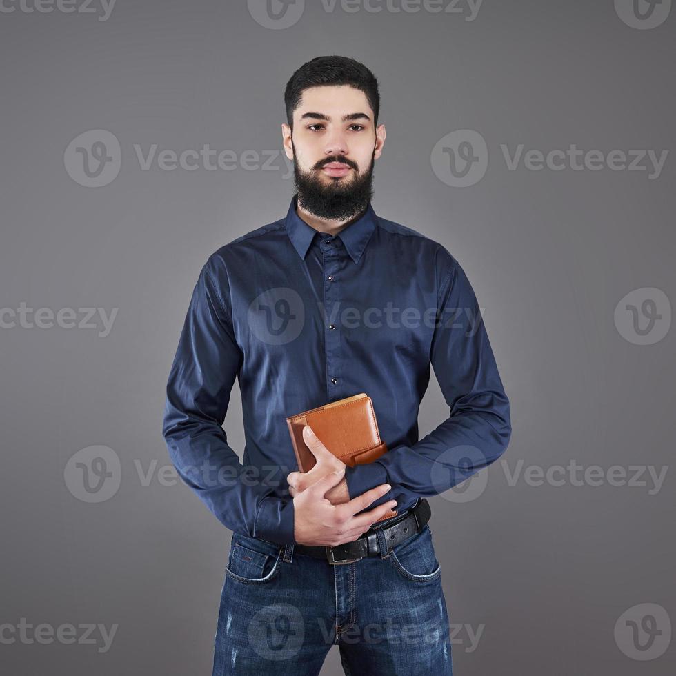 Portrait of toothy handsome bearded man with book on hands photo