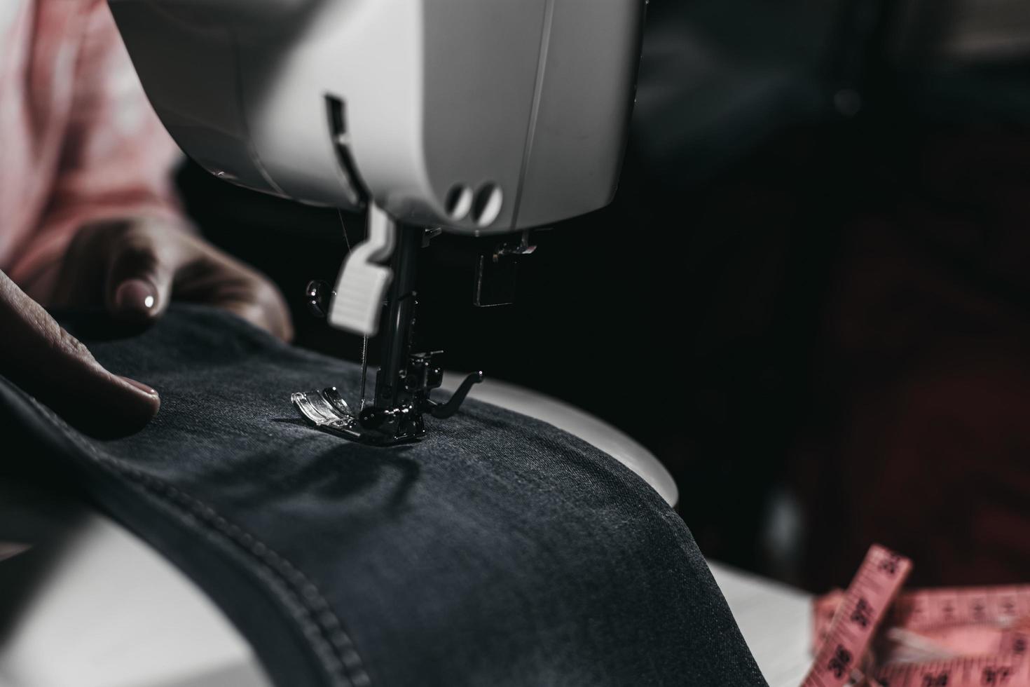 Woman sews clothes on a sewing machine in the frame visible hands. photo