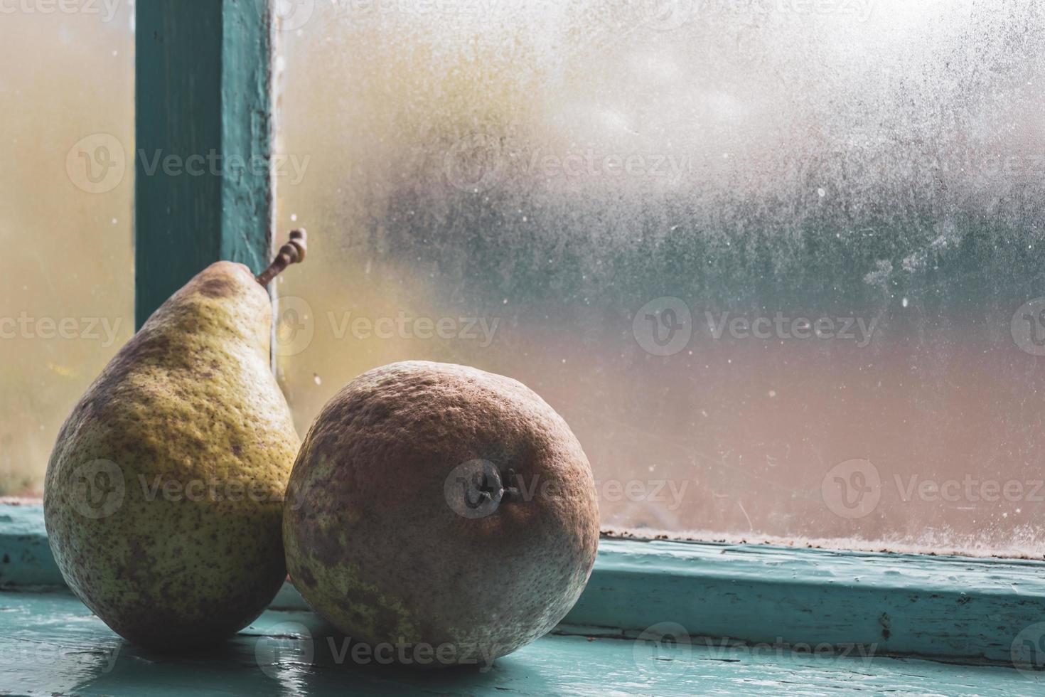 Two large pears after the fall harvest on an old, misted blue window. photo
